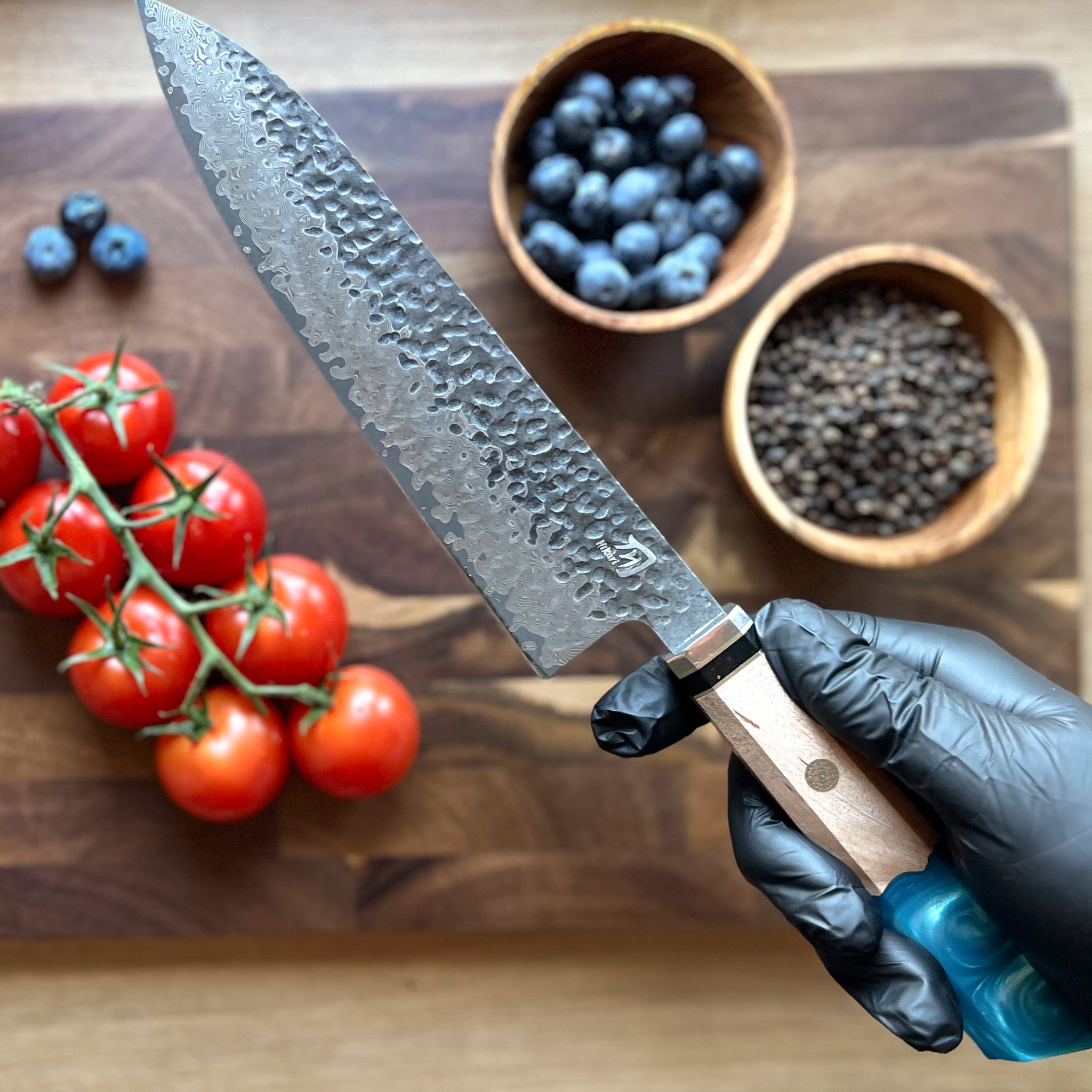 Japanese Kitchen knife in the hands of chef near tomatoes and blueberries